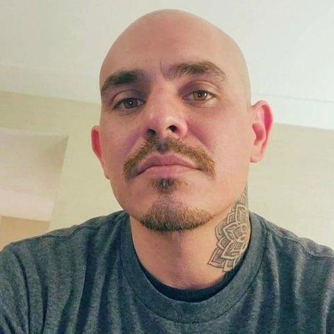 Ed, a man with a shaved head and a mustache, in a grey T-shirt.
